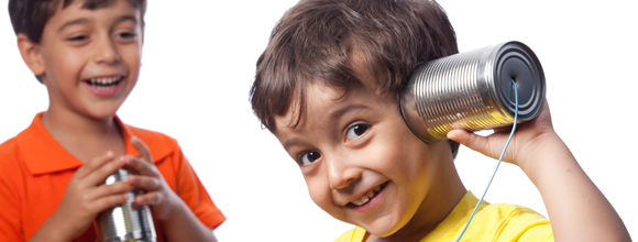 Two boys talking on can phones
